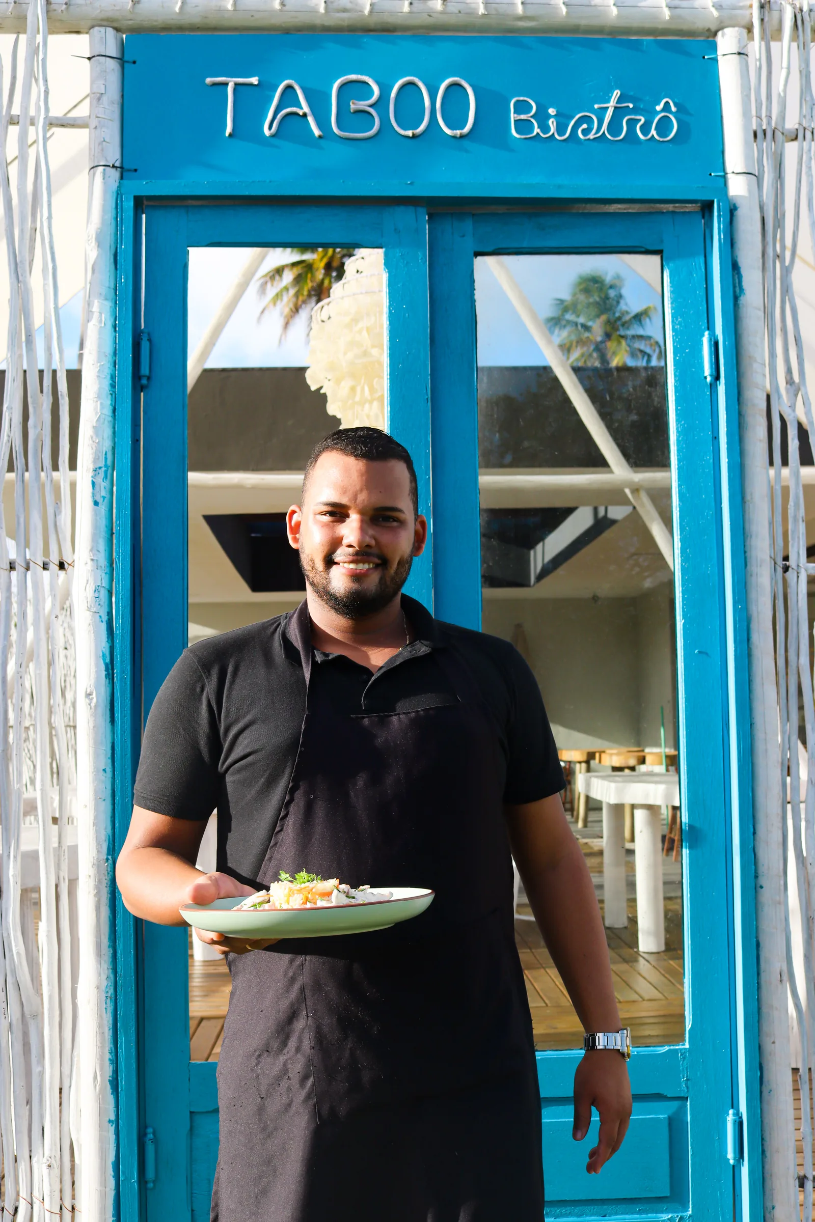 Profissional do Taboo Bistrô apresenta um prato à entrada do restaurante.